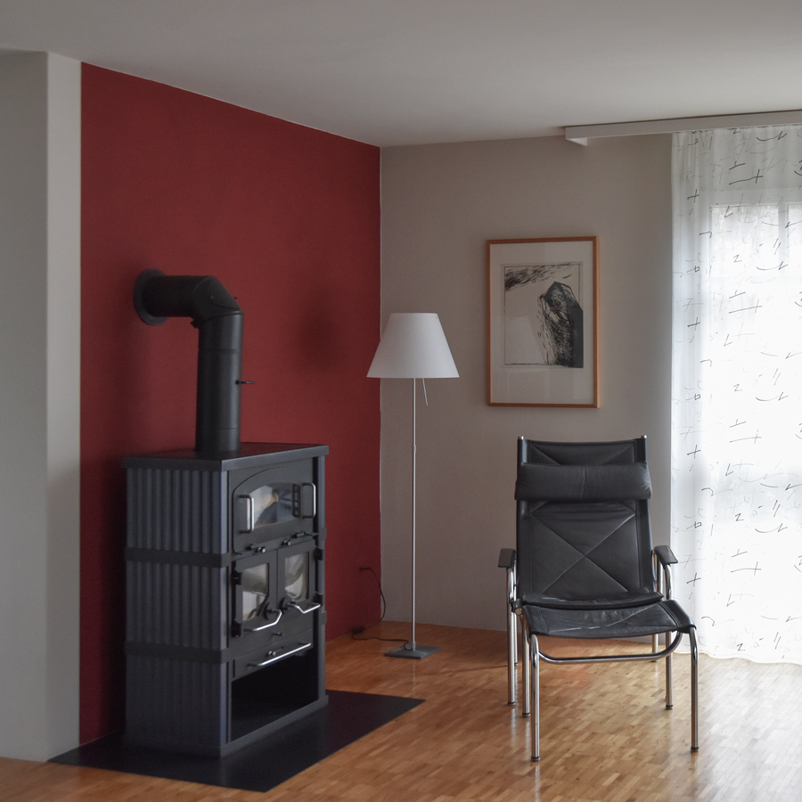 Farbgestaltung + Feng Shui im Innenraum: Das Bild zeigt das Wohnzimmer im Erdgeschoss in hellem Sandton und rubinroter Akzentwand.