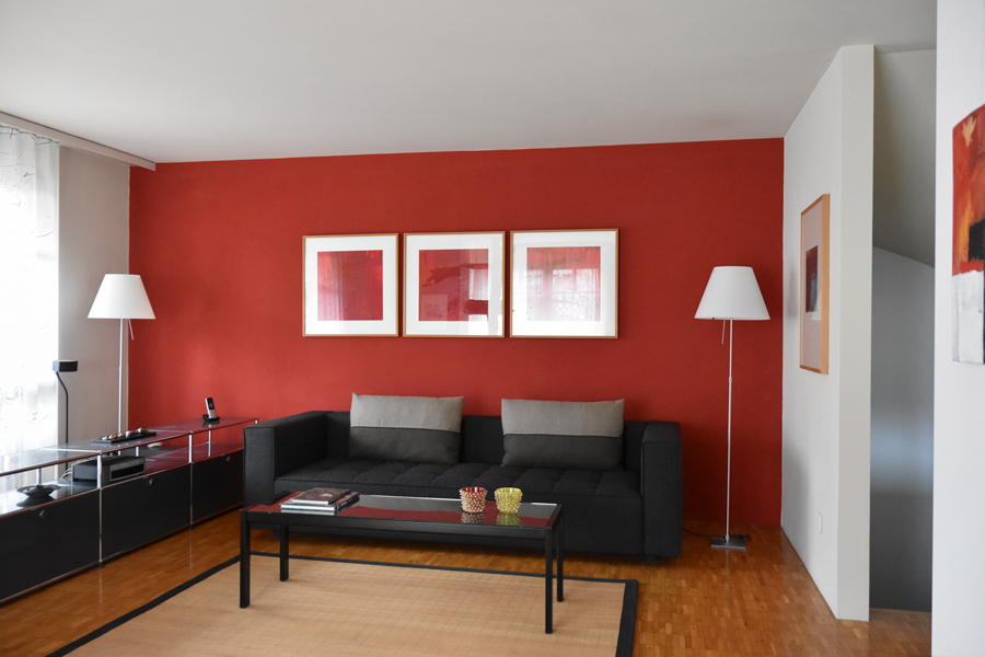 Farbgestaltung + Feng Shui im Innenraum: Das Bild zeigt das Wohnzimmer im Erdgeschoss in hellem Sandton und roter Akzentwand.