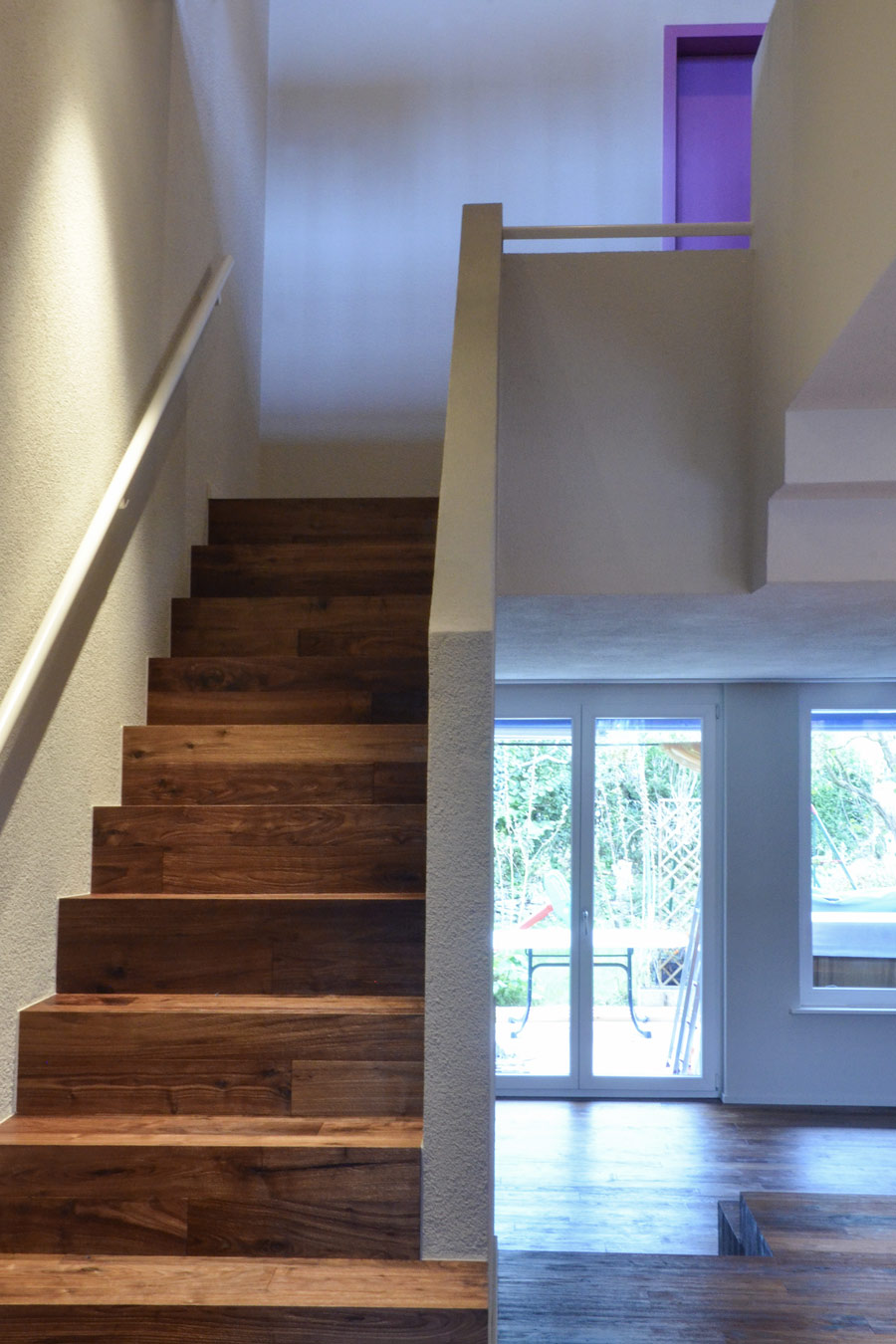 Farbgestaltung Wohnraum: Das Bild zeigt den Blick von der Eingangstür in den offenen Wohnraum und zur Treppe ins Obergeschoss nach der Renovation.