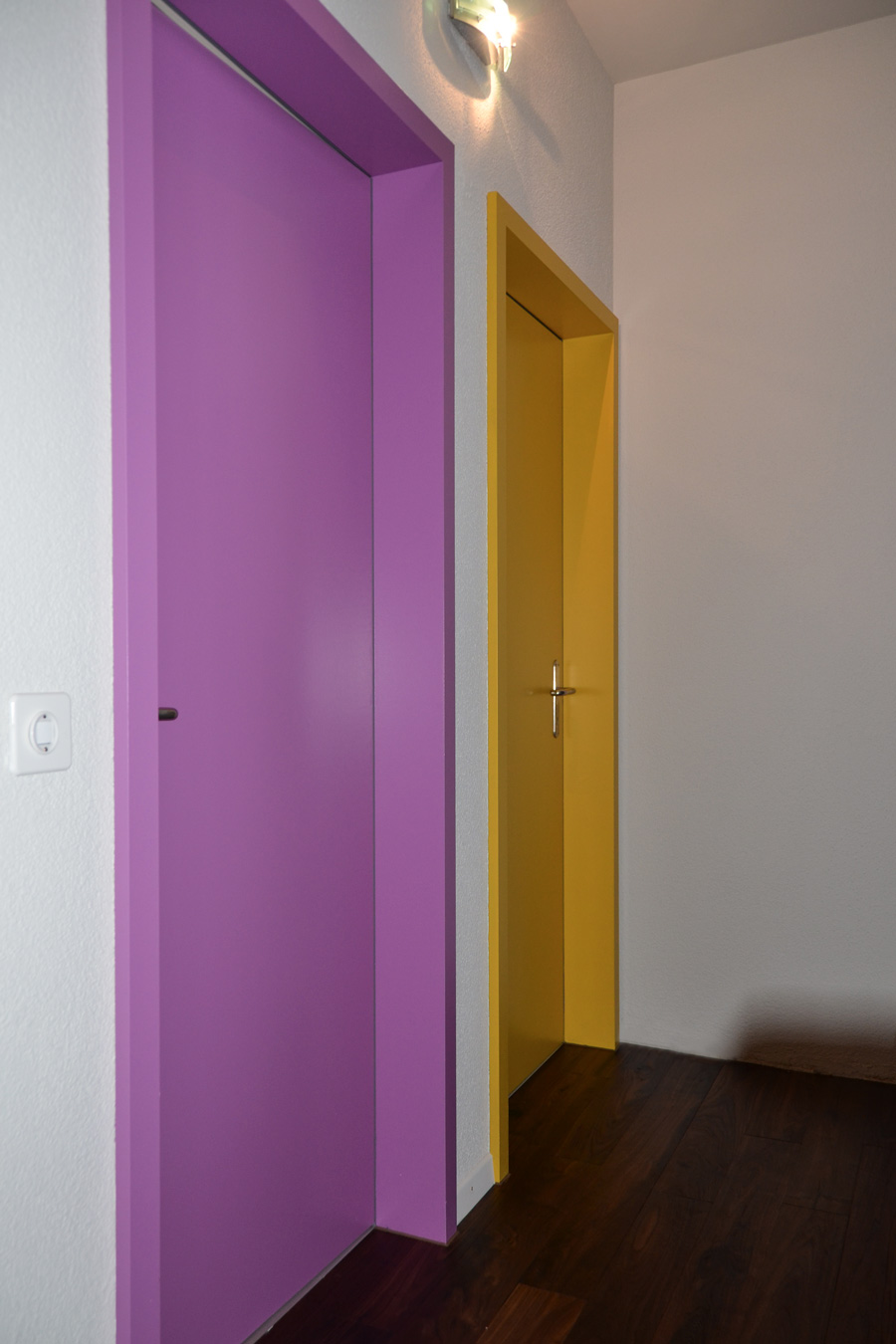 Farbgestaltung Wohnraum: Das Bild zeigt den Flur im Obergeschoss mit den farbigen Türen zu den Kinderzimmern nach der Renovation.