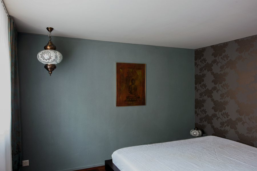 Farbgestaltung Elternschlafzimmer: Das Bild zeigt das Schlafzimmer vom Eingang aus, mit der blaugrauen Wand gegenüber und dem Wandstück mit Tapete rechts.