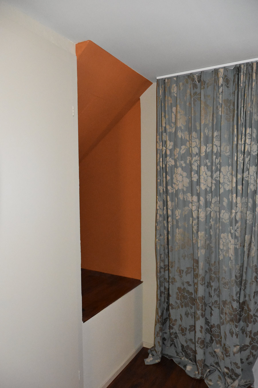 Farbgestaltung Elternschlafzimmer: Das Bild zeigt eine Raumnische neben dem Eingang zum Zimmer, die in einem weichen, herbstlichen Orange gestrichen ist.