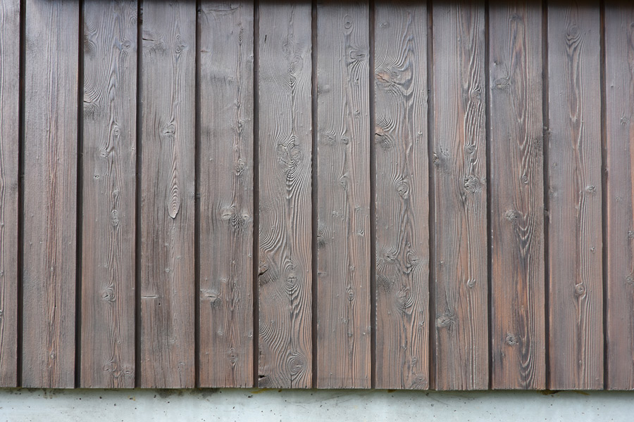 Farbgestaltung Holzfassade: Das Bild zeigt einen Ausschnitt aus der Holzverschalung der renovierten Fassade, die in einem kühlen Braun lasiert wurde.