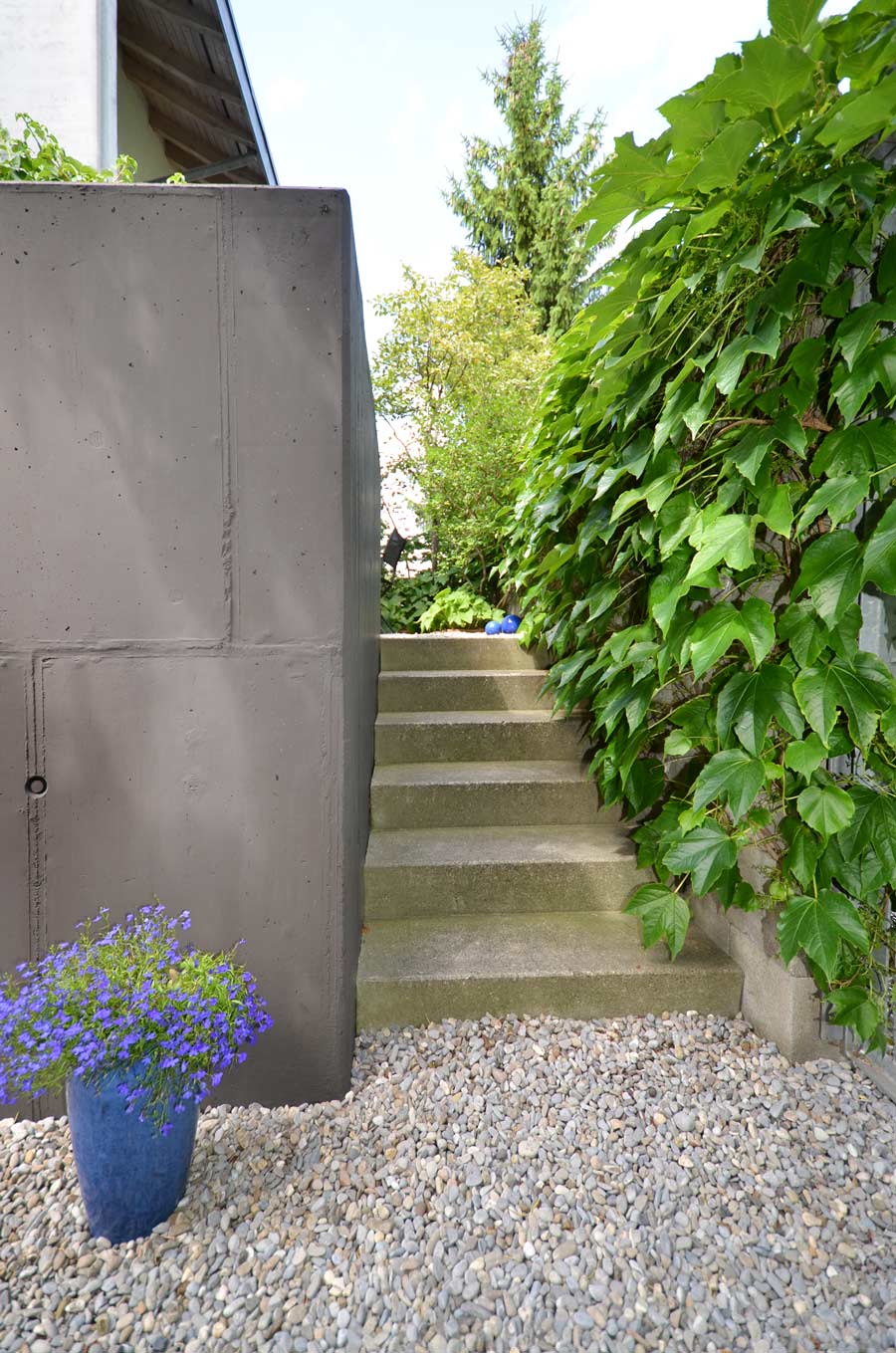 Farbgestaltung im Aussenraum: Das Bild zeigt den Blick vom Eingangsbereich beim Gartentor zum kleinen Hof auf der Nordseite vor dem Esszimmer.