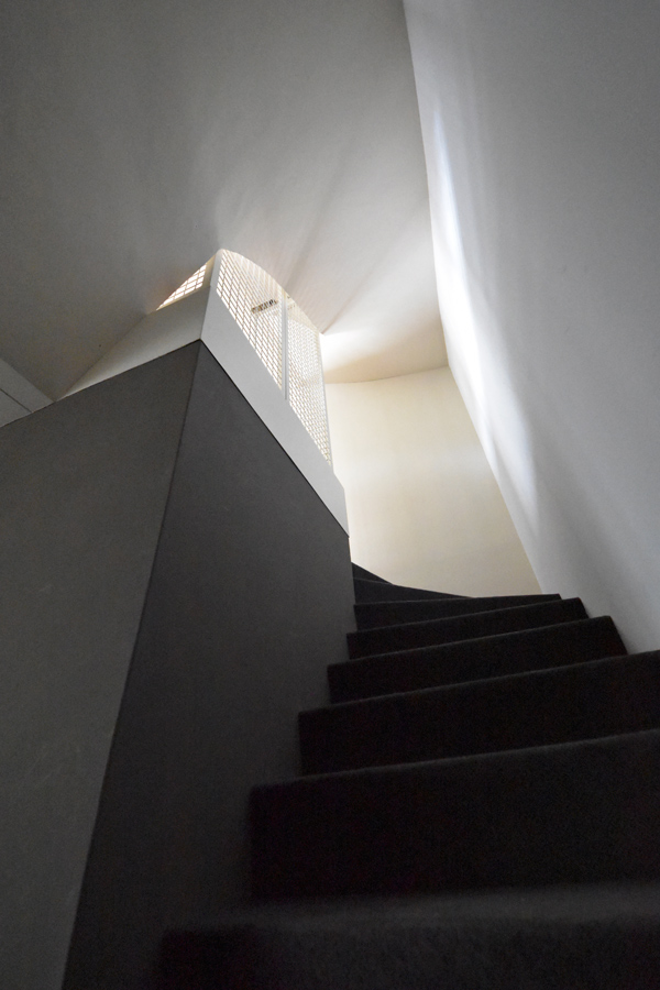 Farbgestaltung + Feng Shui im Innenraum: Das Bild zeigt das Treppenhaus zum Erdgeschoss, das ein Helldunkel-Kontrast zwischen linker Wand in Graubraun und rechter Wand in hellem Lapislazuliblau zeigt.