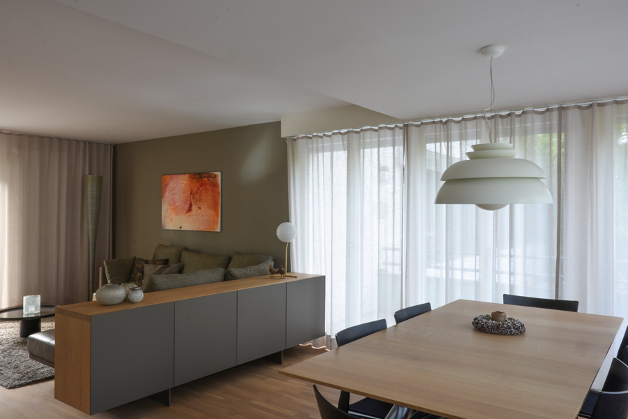 Farbgestaltung Innenraum: Das Bild zeigt den Wohn- und Essbereich mit Akzentwand hinter dem Sofa in mittlerem, erdigem Umbraton.
